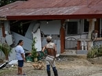 People look at a damaged house in Manay, in the province of Davao Oriental on October 11, 2025, after two powerful quakes struck off the southern Philippines on October 10, killing at least eight people and triggering tsunami warnings. (Photo by Jam STA ROSA / AFP)