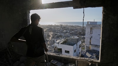 A man looks out from his damaged apartment at the destruction in his neighborhood in Gaza City on October 10, as Israel and Hamas agreed on a ceasefire after two years of conflict. (Jehad Alshrafi/AP)