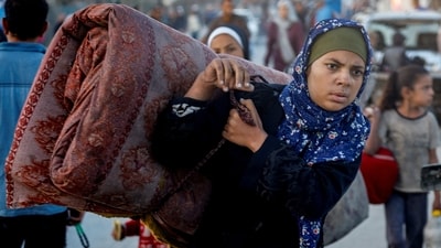 A Palestinian woman is seen carrying a mattress with her as she walks back home with thousands of others who were displaced from their homes due to the two-year old armed conflict between Israel and Hamas. (Mahmoud Issa/REUTERS)