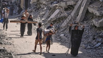 Palestinian kids hold their belongings and walk back home amid destroyed buildings in Khan Younis, southern Gaza Strip on October 10. (AP)