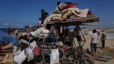 Displaced Palestinians sit and stand next to their belongings piled on a motorcycle near Wadi Gaza in the central Gaza Strip as Israel and Hamas agreed to a ceasefire. (Abdel Kareem Hana/AP)