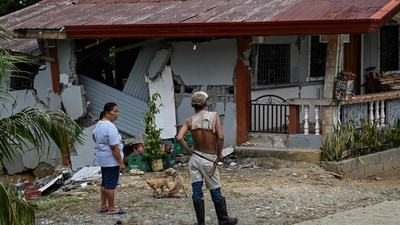 People look at a damaged house in Manay, in the province of Davao Oriental on October 11, 2025, after two powerful quakes struck off the southern Philippines on October 10, killing at least eight people and triggering tsunami warnings. (Photo by Jam STA ROSA / AFP) (AFP) People look at a damaged house in Manay, in the province of Davao Oriental on October 11, 2025, after two powerful quakes struck off the southern Philippines on October 10, killing at least eight people and triggering tsunami warnings. (Photo by Jam STA ROSA / AFP) (AFP)