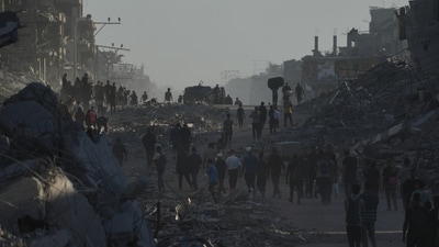 Palestinians walk back to their homes in Gaza through the heavily devastated Al-Jalaa Street in Gaza City on October 11 as Isarel and Hamas agree to pause their conflict after two years. (Abdel Kareem Hana/AP)