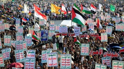 Supporters of Yemen's Huthis raise placards and flags as they gather to celebrate the ceasefire in the Gaza Strip on October 10, 2025. (Mohammed Huwais/AFP)