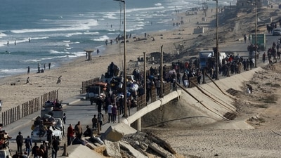 Palestinians walk along the coast as they had home in Gaza after two years of conflict in the region. (Mahmoud Issa/REUTERS)