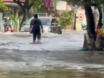 A man is seen wading through nearly knee-deep water in Bengaluru's infamous Rainbow Drive area as a car also pushes through.