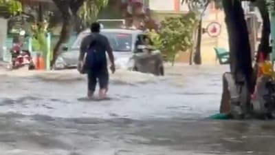 A man is seen wading through nearly knee-deep water in Bengaluru's infamous Rainbow Drive area as a car also pushes through. A man is seen wading through nearly knee-deep water in Bengaluru's infamous Rainbow Drive area as a car also pushes through.