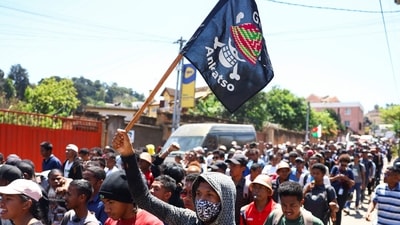 A protester carries a banner featuring a Malagasy version of the logo of the popular Japanese manga One Piece, a symbol adopted by Gen Z protest movements worldwide. He marches along with other protestors during a nationwide youth-led demonstration in Antananarivo, Madagascar, over frequent power outages and water shortages. (Reuters)