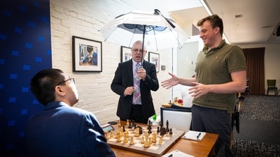 Chris Bird holds an umbrella for Hans Niemann and Wesley So. (X) Chris Bird holds an umbrella for Hans Niemann and Wesley So. (X)