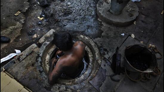 NEW DELHI, INDIA - SEPTEMBER 18,2013: municipal worker attempts to unblock a sewer overflowing with human excreta in New Delhi on October 7, 2009. Although a law bans manual scavenging - the manual removal of human excreta from 'dry toilets' - the practice is widespread across cities and towns in India. (Photograph by Raj K Raj / Hindustan Times)