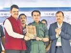 Gadchiroli: Maharashtra Chief Minister Devendra Fadnavis presents a copy of the Constitution of India to Senior Naxal leader Mallojula Venugopal Rao alias Bhupathi as the latter along with 60 other cadres surrendered, in Gadchiroli, Wednesday, Oct. 15, 2025. (PTI Photo)(PTI10_15_2025_000125B) (PTI)