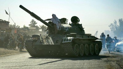 Taliban security personnel on a Soviet-era tank are followed by motorcyclists as they ride towards the border, as clashes take place between Taliban security personnel and Pakistani border forces, in the Spin Boldak district of Kandahar Province on October 15, 2025. Fifteen civilians were killed and dozens wounded in fresh clashes on the border between Afghanistan and Pakistan, Afghan officials told AFP on October 15. (Photo by Sanaullah SEIAM / AFP) (AFP)