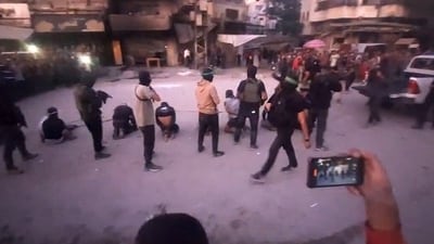 Armed Hamas fighters standing behind blindfolded, bound and kneeling men as a crowd surrounds them in a street in Gaza City. (AFP) Armed Hamas fighters standing behind blindfolded, bound and kneeling men as a crowd surrounds them in a street in Gaza City. (AFP)