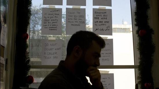 In this Monday, Dec. 23, 2019 photo, words of encouragement are taped to a window next to Bassem, a volunteer, as he waits for calls at at Lebanon's Embrace, a mental health organization operating the national suicide prevention helpline in Beirut. Lebanon is entering its third month of protests, the economic pinch is hurting everyone, and the government is paralyzed. So people are resorting to what they've done in previous crises: They rely on each other, not the state. (AP Photo/Maya Alleruzzo) (AP)