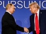 Donald Trump and Vladimir Putin shake hands during a press conference
