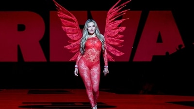 Karol G walked the runway in a bright red sheer bodysuit with floral detailing, looking absolutely fiery. (REUTERS)