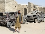 A Taliban fighter stands next to vehicles destroyed during an airstrike amid the conflict between Afghanistan and Pakistan, in Spin Boldak district of Kandahar Province, Afghanistan.