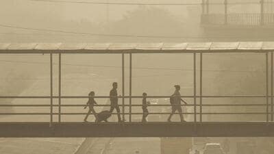 People cross a footover bridge amid low visibility in Gurugram on Friday. (PTI) People cross a footover bridge amid low visibility in Gurugram on Friday. (PTI)