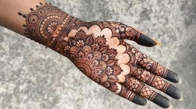 This gorgeous mehndi design features a large, densely detailed half-mandala dominating the palm, connected to a wide cuff-style wrist band and complemented by intricate finger patterns with darkened tips. (Pinterest) This gorgeous mehndi design features a large, densely detailed half-mandala dominating the palm, connected to a wide cuff-style wrist band and complemented by intricate finger patterns with darkened tips. (Pinterest)