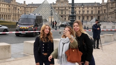 Tourists make a selfie in the courtyard of the closed Louvre museum after a robbery on Sunday. (AP) Tourists make a selfie in the courtyard of the closed Louvre museum after a robbery on Sunday. (AP)