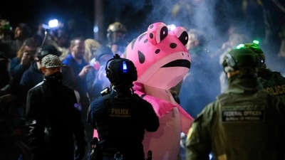 An anti ICE protestor wears an inflatable costume and stands against federal guards as citizens protested again the US government on October 18, 2025. (Mathieu Lewis-Rolland/Getty Images via AFP)