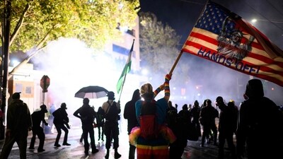 Anti ICE protestors hold a flag which reads ‘hands off’ as they approach the US immigration and customs enforcement building on October 18, 2025 in Portland. (Mathieu Lewis-Rolland/Getty Images via AFP)