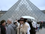 People queue in the Louvre pyramid courtyard moments before the announcement the museum will remain closed for a second day running after thieves stole crown jewels.