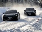 Porsche Taycan driving on a snow-covered road in a winter environment.