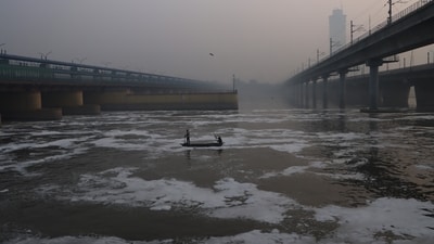 Fishermen catch fish amid floating foam in the Yamuna river, near Kalindi Kunj area, in New Delhi on Monday. (ANI Photo) (Sathiya)