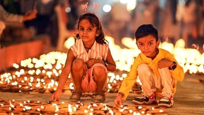 Two kids light earthen oil lamps on the eve of Diwali in Uttar Pradesh's Ayodhya on Sunday. (ANI)