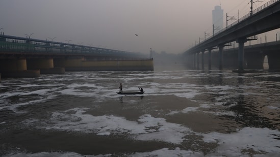 Fishermen catch fish amid floating foam in the Yamuna river, near Kalindi Kunj area, in New Delhi on Monday. (ANI Photo)(Sathiya)