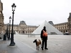 A security employee with a dog stands near the glass Pyramid of the Louvre Museum in Paris, France, October 20, 2025.