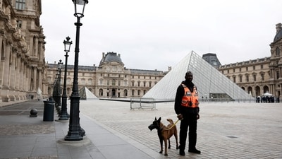 A security employee with a dog stands near the glass Pyramid of the Louvre Museum in Paris, France, October 20, 2025. (Reuters)