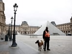 A security employee with a dog stands near the glass Pyramid of the Louvre Museum in Paris, France, October 20, 2025.