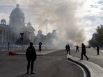 Police officers secure the area as smoke rises from a burning tent following an incident in front of the Parliament in Belgrade, Serbia, October 22, 2025.