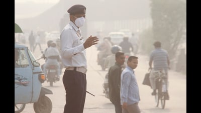 A traffic policeman wears a mask as he manages traffic amid low visibility after air quality deteriorated across northern India, in Gurugram on Wednesday. (PTI) A traffic policeman wears a mask as he manages traffic amid low visibility after air quality deteriorated across northern India, in Gurugram on Wednesday. (PTI)