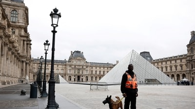 A security employee with a dog stands near the glass Pyramid of the Louvre Museum in Paris, France, October 20, 2025. (Reuters)