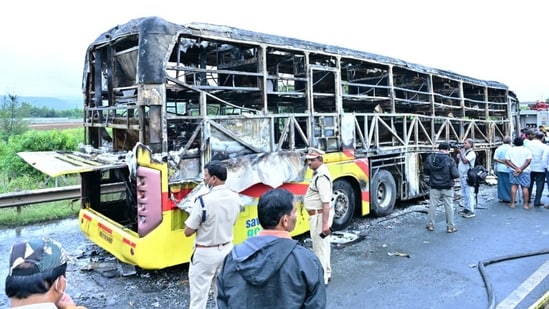 Police personnel investigate the spot after a Hyderabad-bound private bus caught fire following a collision with a two-wheeler, near Chinnatekur in Kurnool, Andhra Pradesh(PTI)
