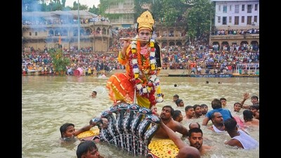 An artiste dressed up as Lord Sri Krishna, jumped on the hood of Kalia Naag in the Ganga (Rajesh Kumar/HT)