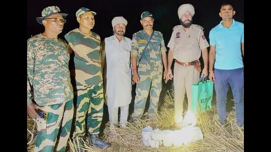 Security personnel with the contraband recovered from a field at Jalloke village in Ferozepur district on Saturday. (HT Photo)