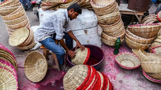 A Worker paints the bamboo baskets for the Chhath puja festival at a market, in Prayagraj, UP(Nitin Sharma/ANI)