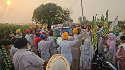 Farmers surround a police vehicle in Qila Bharian village of Sangrur on Tuesday.