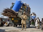 A Taliban security personnel stands guard as deported Afghan refugees from Pakistan arrive at the zero-point border crossing between Afghanistan and Pakistan