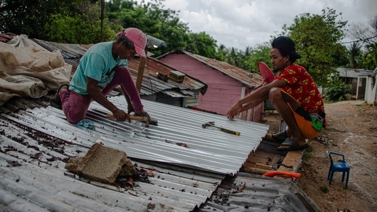 Two man fix the roof of a house ahead of the arrival of Hurricane Melissa in Barahona, Dominican Republic on October 28, 2025. (Photo by Carlos FABAL / AFP)(AFP)