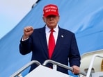 \President Donald Trump gestures, while wearing a "Make America Great Again" cap, as he disembarks Air Force One.