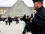 A French CRS riot police officer patrols near the glass Pyramid of the Louvre Museum, after French police arrested suspects in the Louvre heist case, in Paris, France.