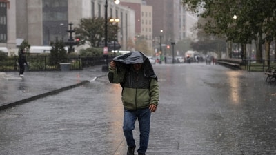 A person walks in the rain during heavy downpour on October 30, 2025 New York City. (AFP)
