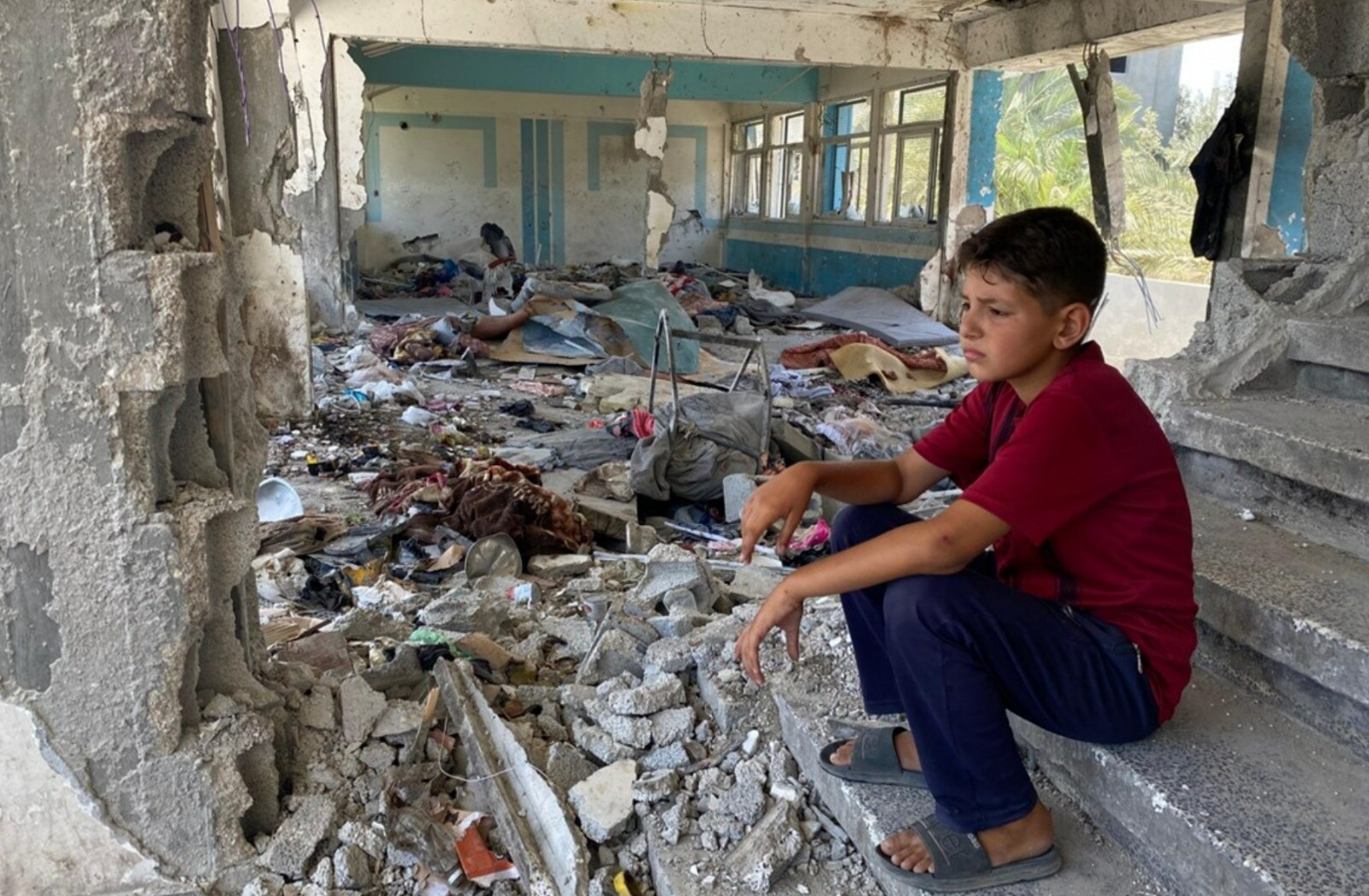 A child sits among the ruins of a school in Nuseirat; 2024. (Photo by Fadi Thabet for United Nations Relief and Works Agency (UNRWA)) A child sits among the ruins of a school in Nuseirat; 2024. (Photo by Fadi Thabet for United Nations Relief and Works Agency (UNRWA))