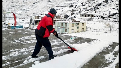 A man clears a rooftop of snow in Lahaul on Wednesday. (PTI)