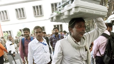 Officials escorted by security personnel carry electronic voting machines (EVMs) for polling stations in Patna, Bihar. (Santosh Kumar/HT Photo)